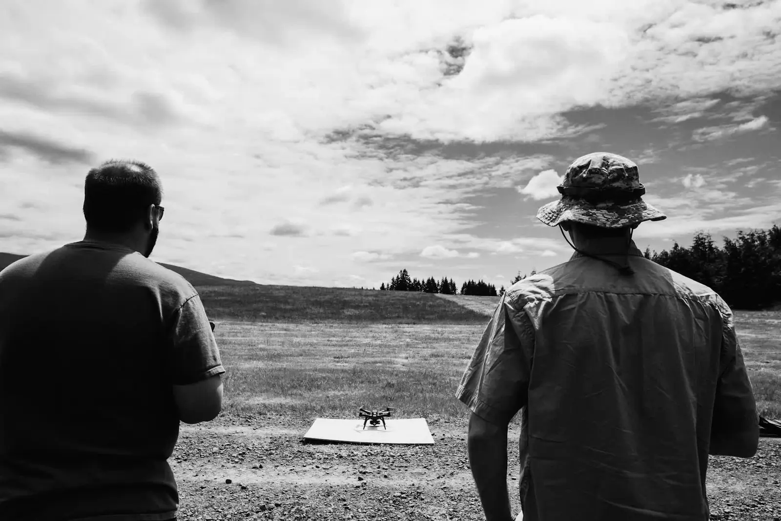 Hai người điều khiển drone cất cánh trên bãi cỏ
